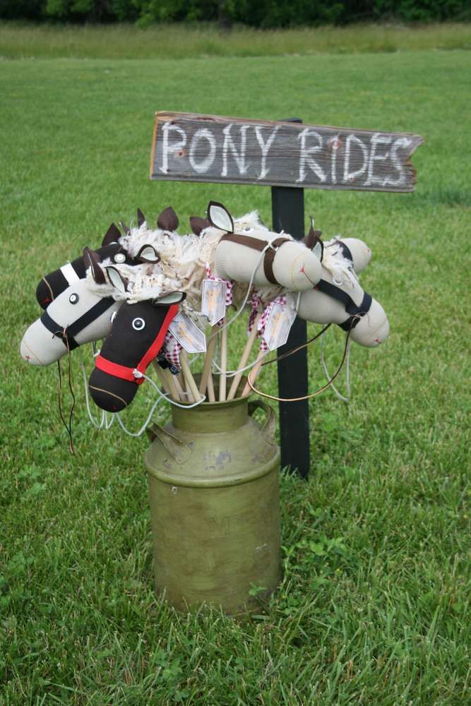 a bunch of stuffed animals sitting on top of a green field next to a sign that says pony rides