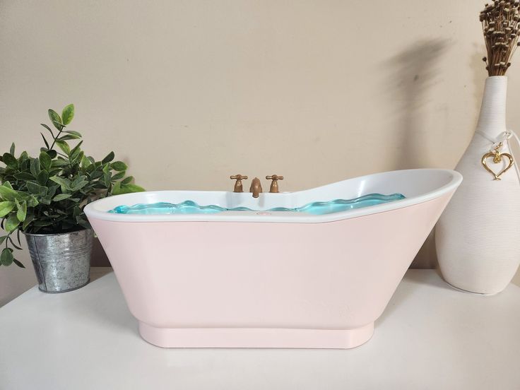 a pink bath tub sitting on top of a white counter next to a vase with flowers