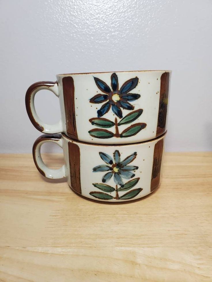 two coffee cups sitting on top of a wooden table