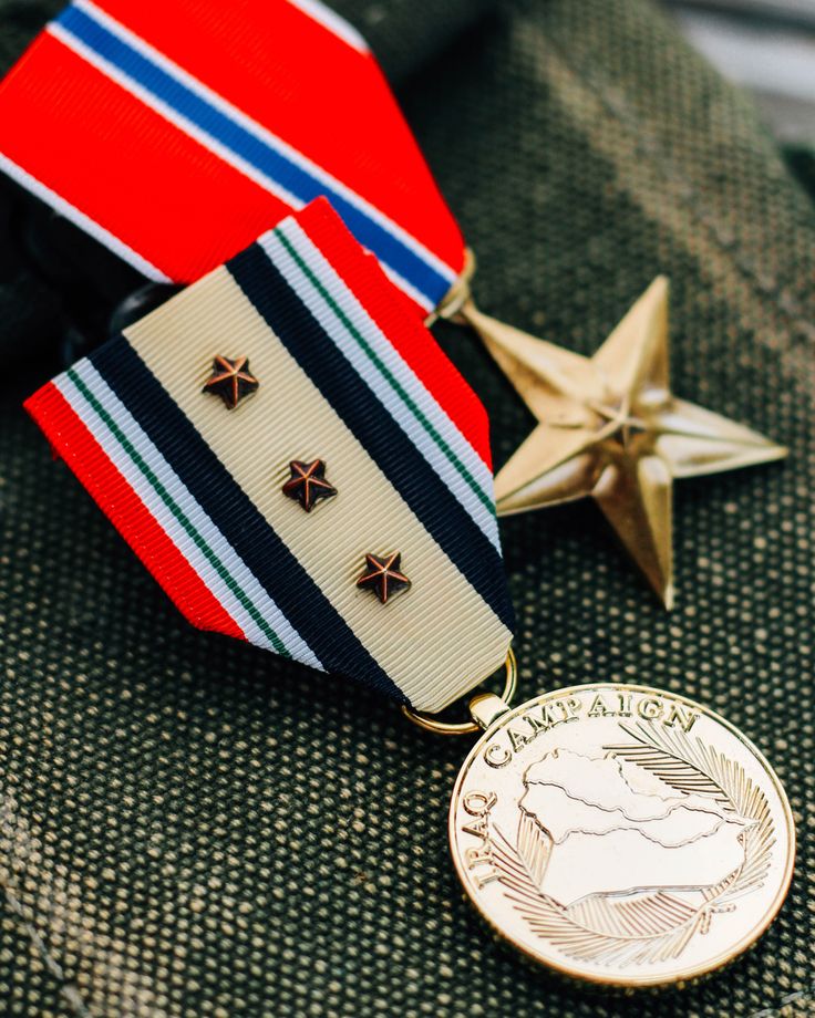 two medals are sitting next to each other on a uniform jacket, one has a gold medal and the other is an american flag