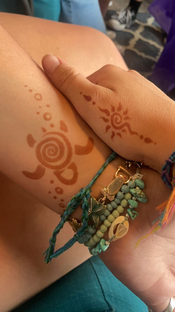 a woman's arm with hendi tattoos and bracelets on her left wrist