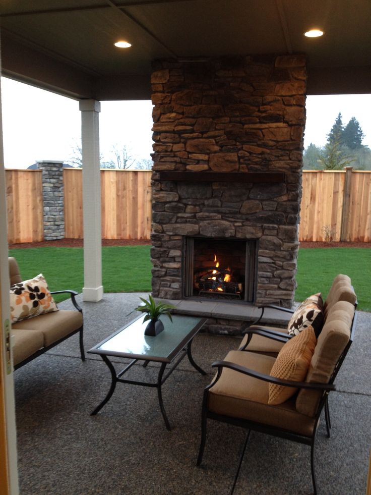 an outdoor living area with couches, tables and a fire place in the center