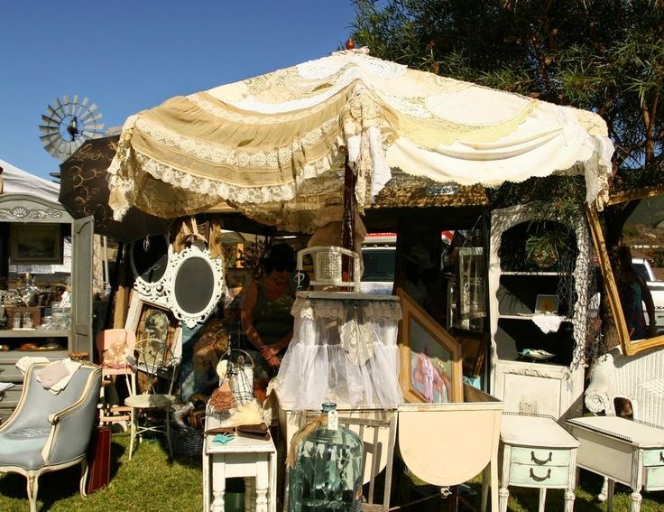 an outdoor flea market with old furniture and other items on the grass in front of it