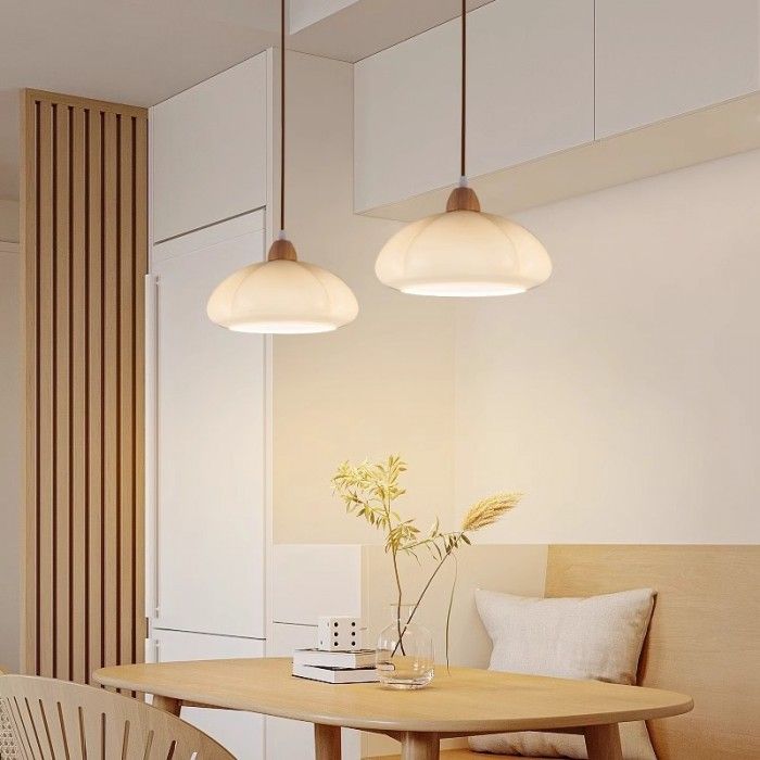 two lights hanging over a wooden table in a living room next to a white wall