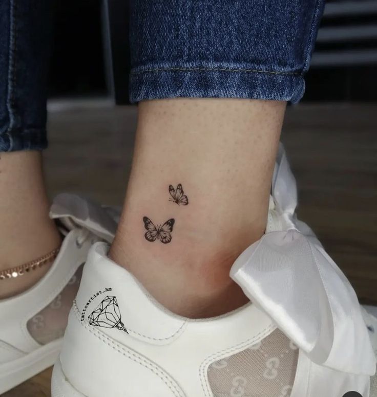 a woman's foot with two small butterflies on the left side of her ankle