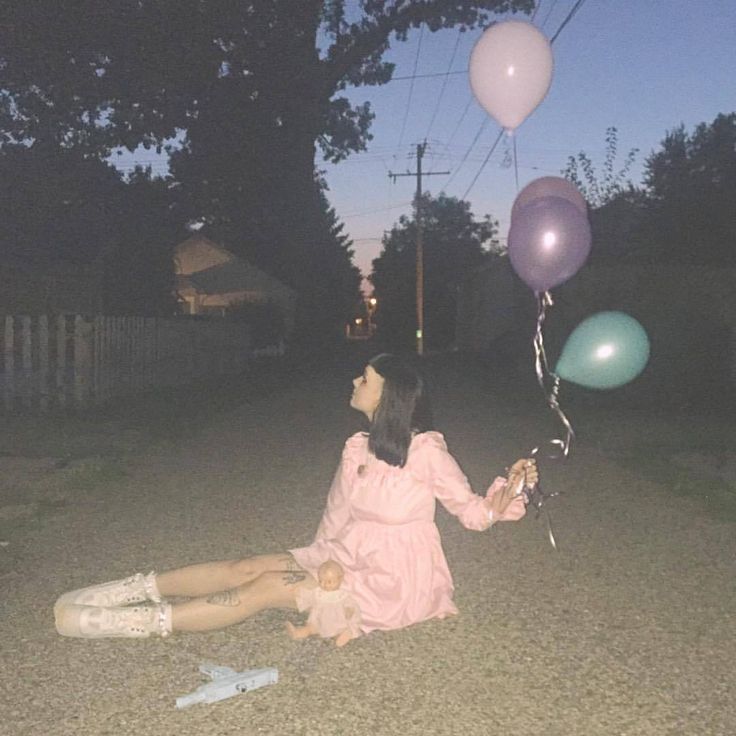 a woman sitting on the ground with balloons