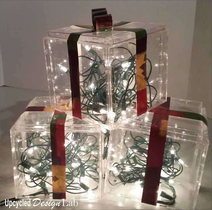 four clear boxes with lights in them and ribbons tied to the sides, all stacked on top of each other