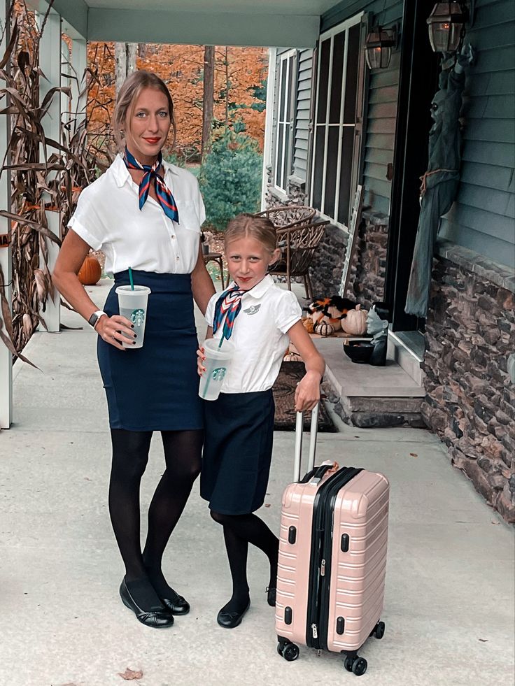 a woman standing next to a little boy in front of a house with suitcases