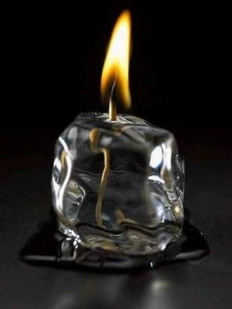 a lit candle is sitting on top of a glass block with water and ice cubes around it