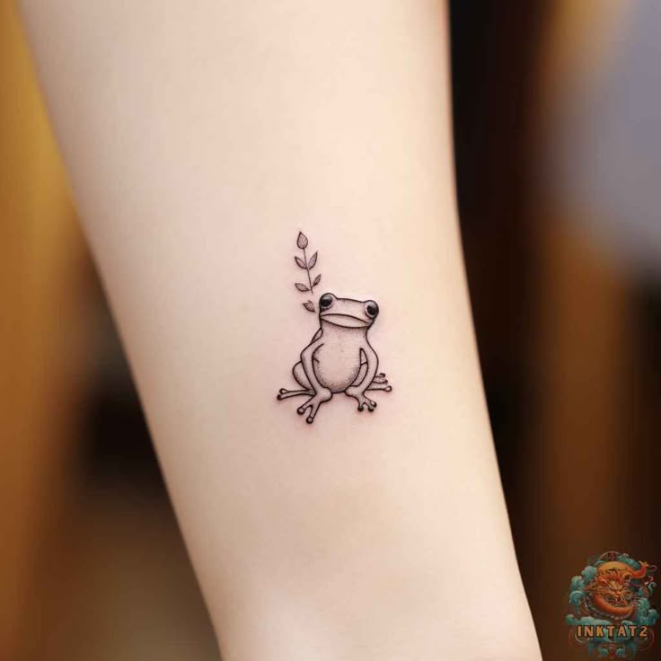 a small frog tattoo on the left side of the leg, with leaves coming out of it