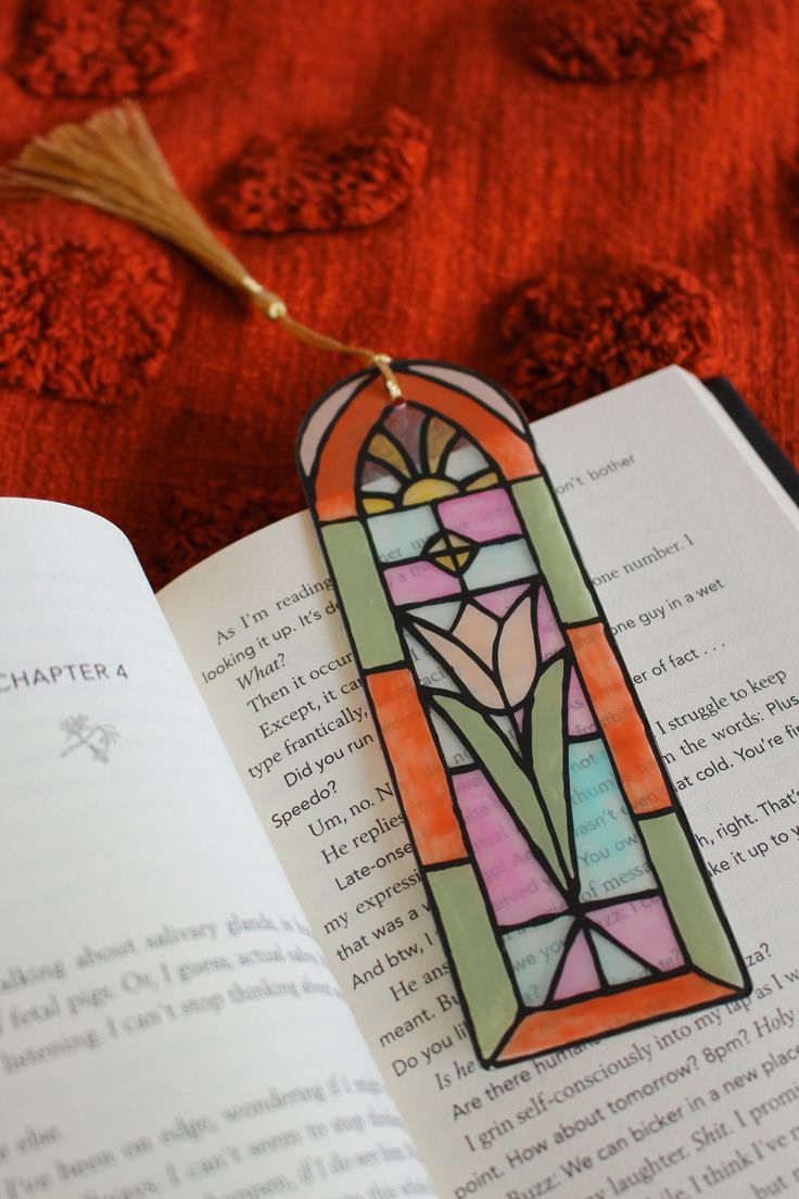 an open book with a stained glass window on it's cover and a tassel