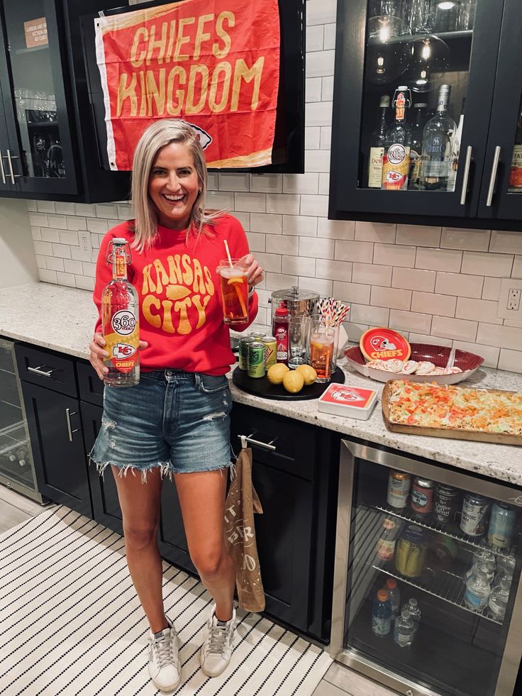 a woman standing in front of a counter with pizza and drinks