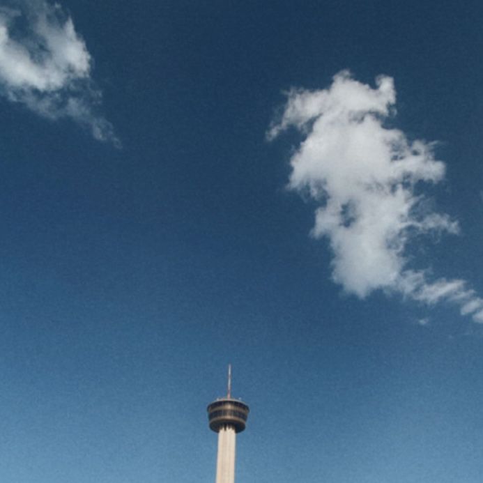 an airplane is flying in the sky near a tall tower with a clock on it