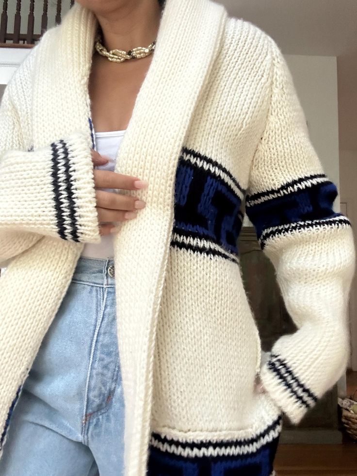 a woman wearing a white cardigan sweater with black and blue stripes on the sleeves