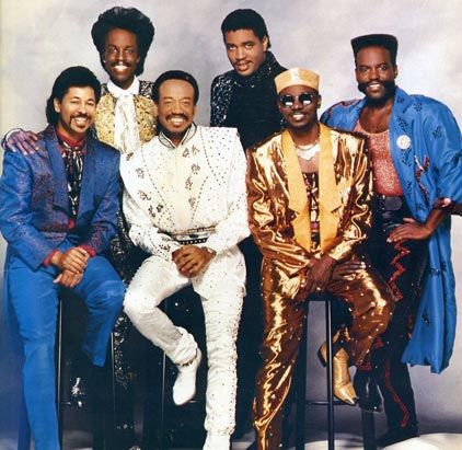 a group of men sitting next to each other in front of a white background with gold and blue outfits