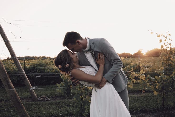 a bride and groom kissing in front of some vines at their farm wedding reception venue