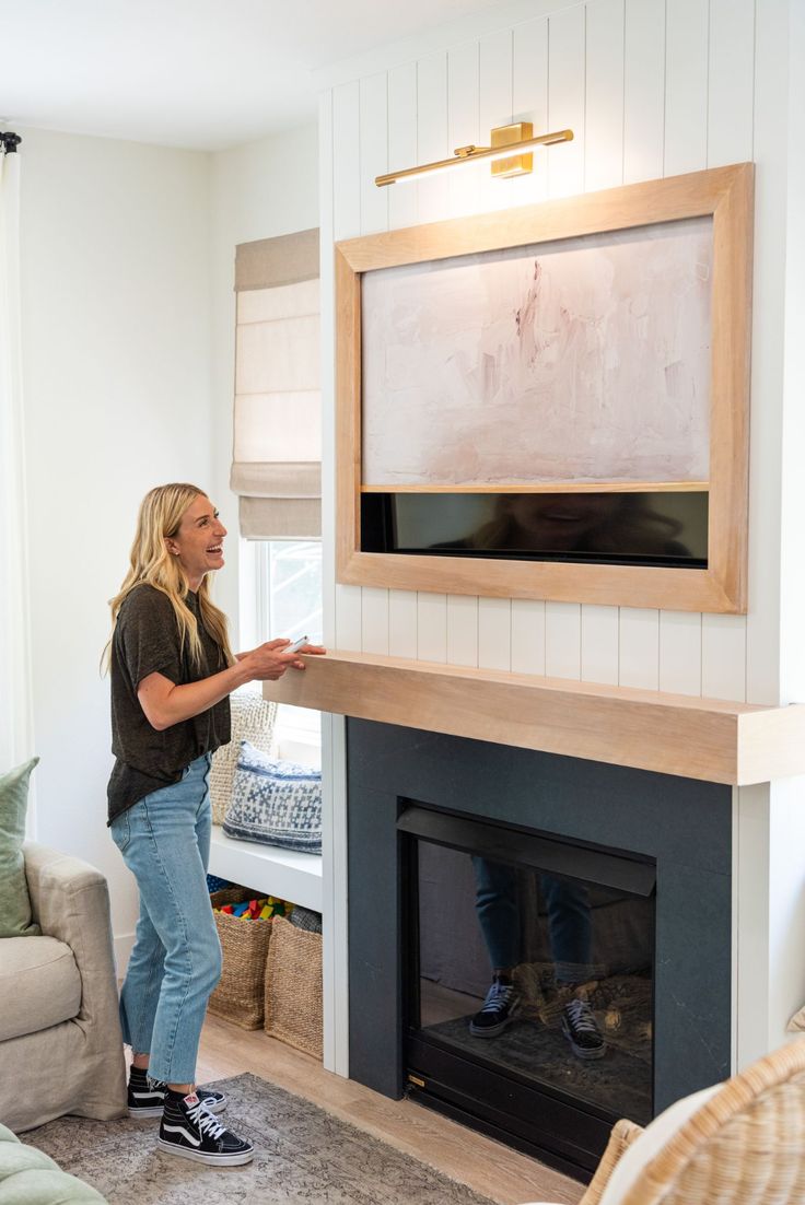 a woman standing next to a fireplace in a living room