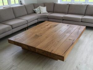 a large wooden table sitting in the middle of a living room next to a couch