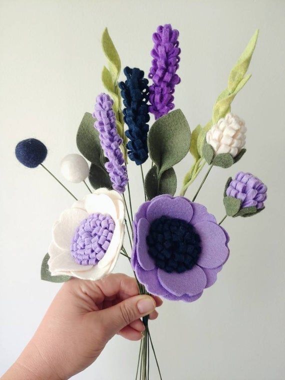 a hand holding a vase filled with purple and white flowers