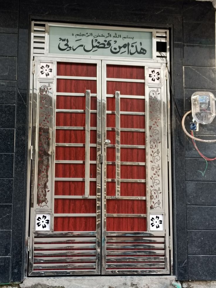 the door to an apartment building is decorated with metal bars and red curtained doors