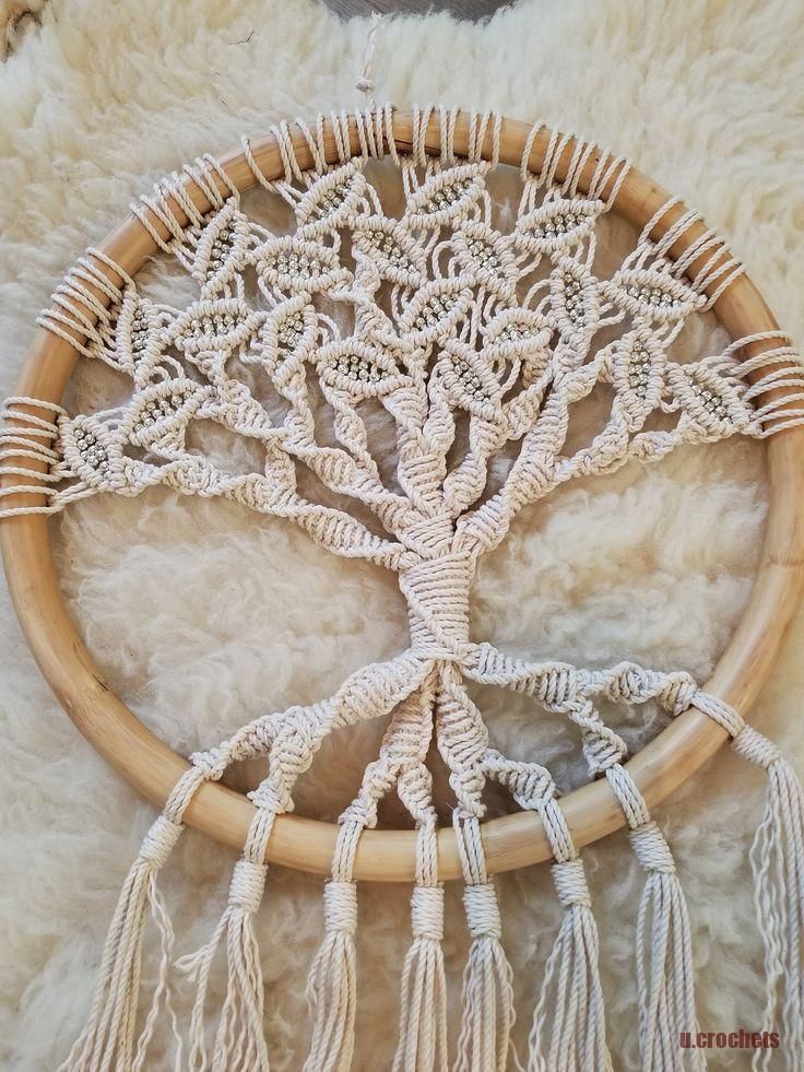 a handmade dream catcher is shown on a furry surface with white yarn and wood