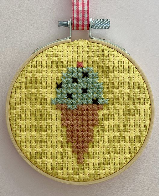 a cross stitch ice cream cone hanging on a wall