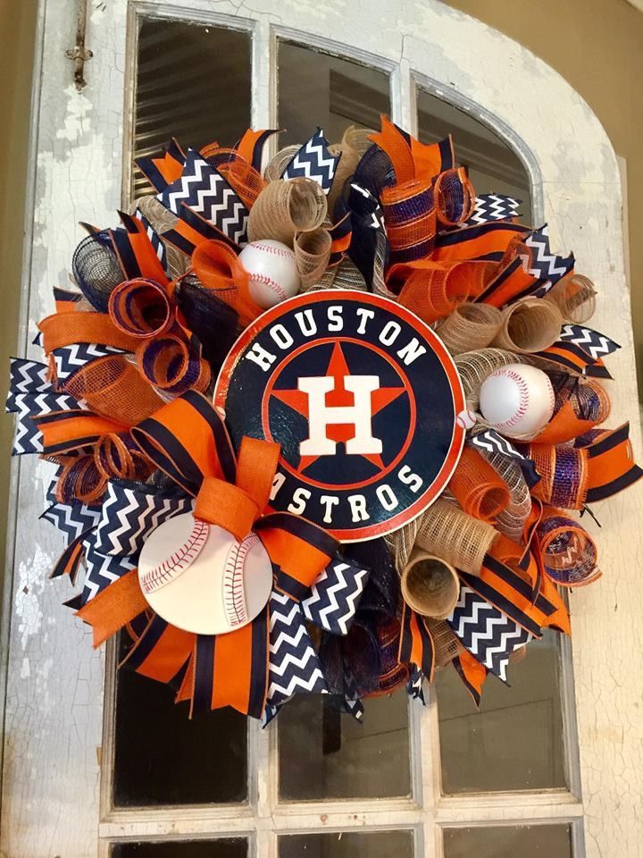 a houston astros wreath with baseballs and other sports items hanging on the front door