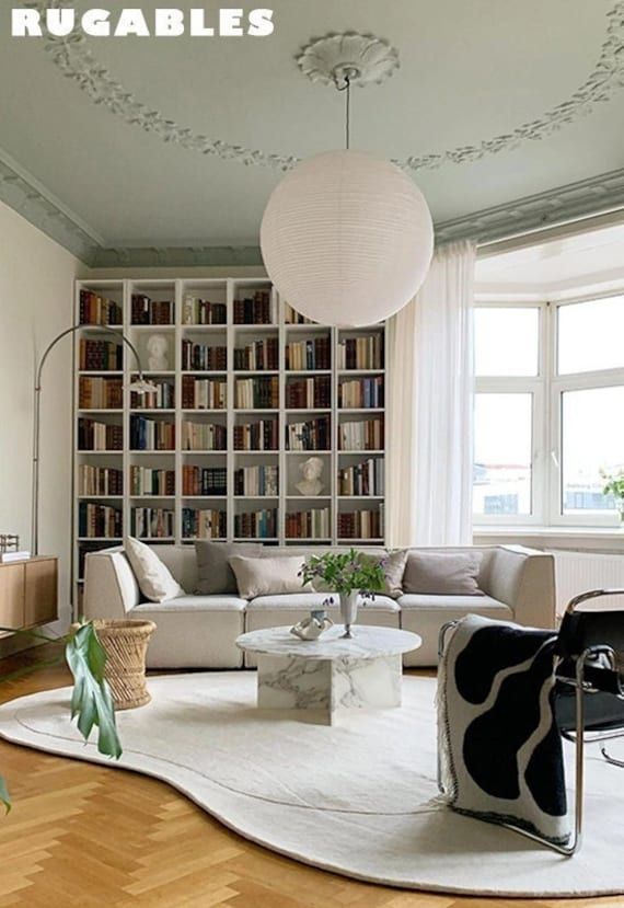 a living room filled with lots of furniture and bookshelves next to a window