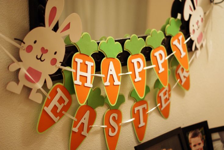 a happy easter bunting banner hanging from a wall with pictures on the wall behind it