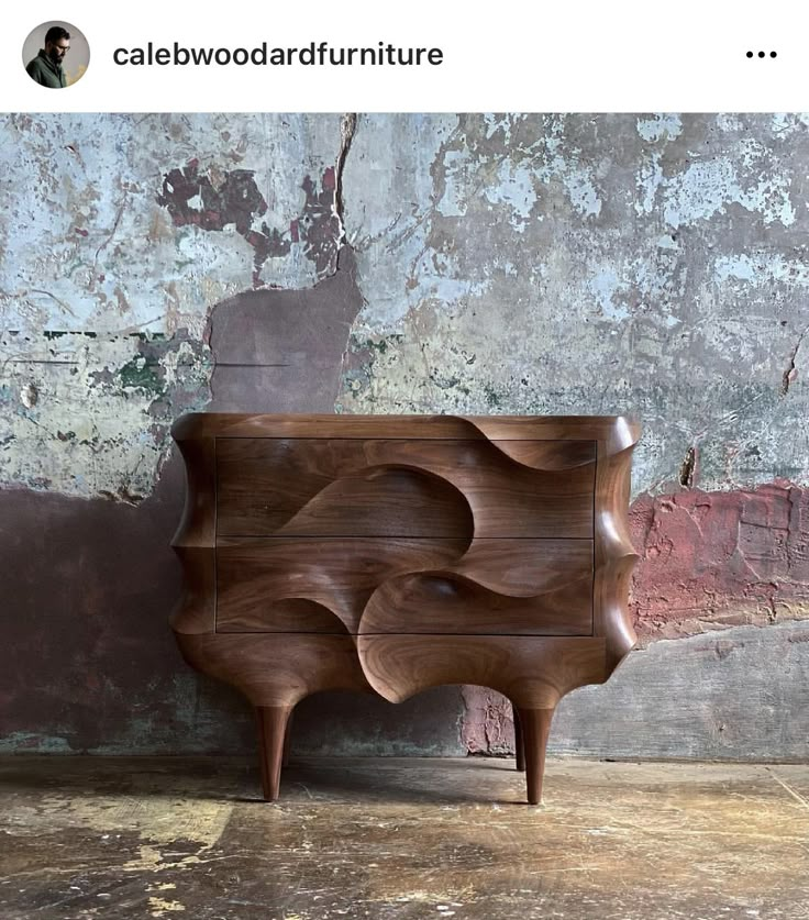 a wooden dresser sitting on top of a floor next to a wall with peeling paint