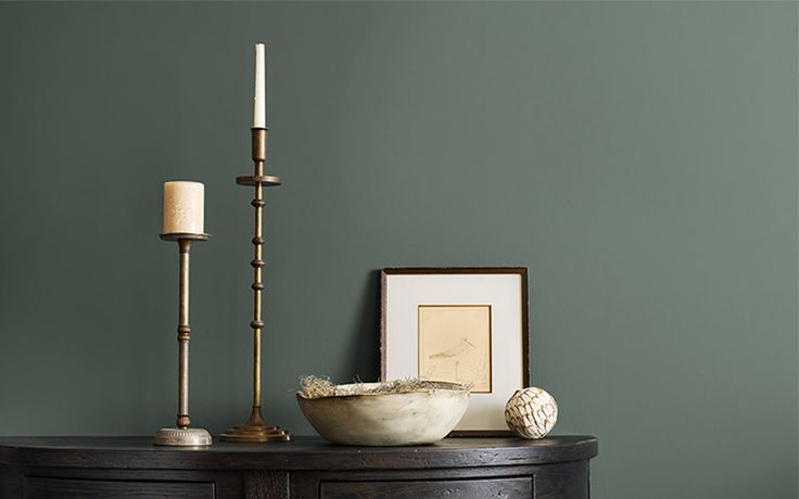 a table with a bowl and two candles on it next to a framed photograph, candle holder and other items