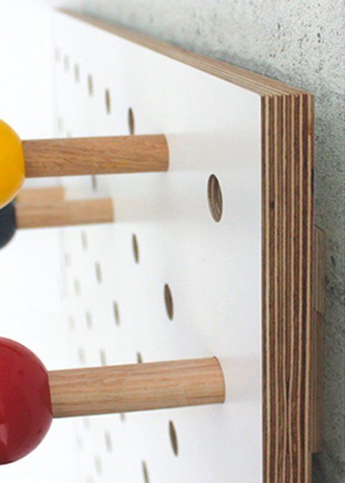 two wooden spoons are hanging on the wall next to a mirror with holes in it