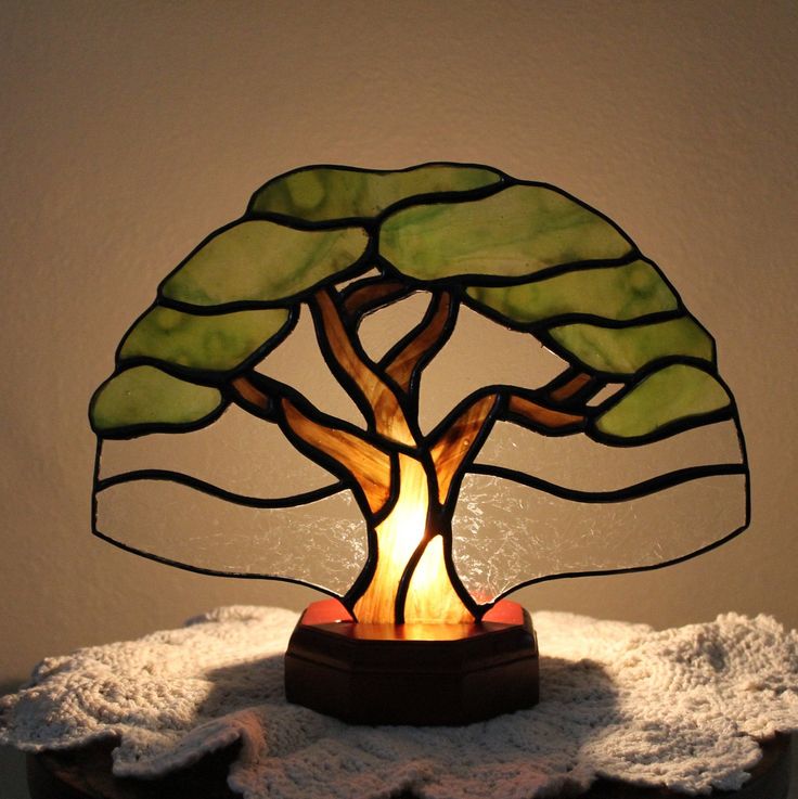 a stained glass lamp with a tree on it's base sitting on a table