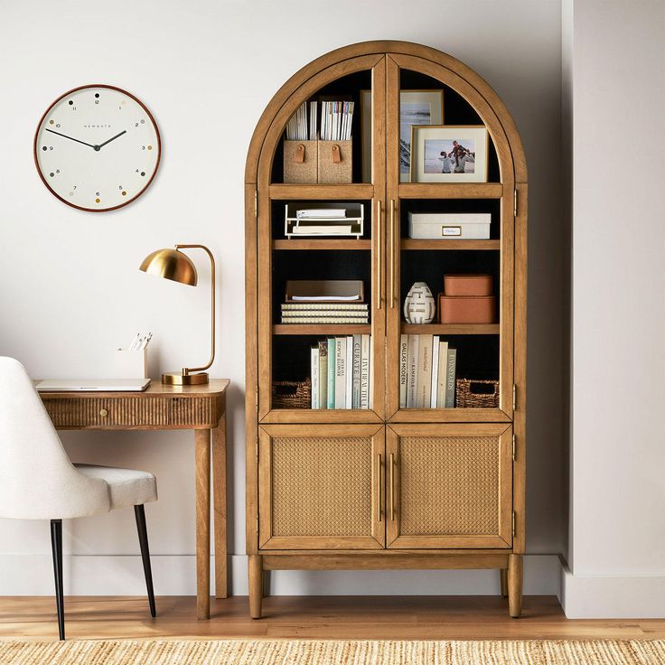 a room with a desk, chair and bookshelf in front of a clock