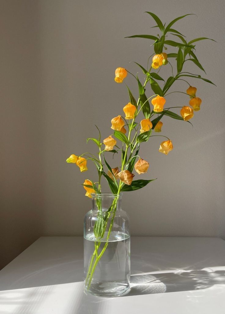 a glass vase with yellow flowers in it