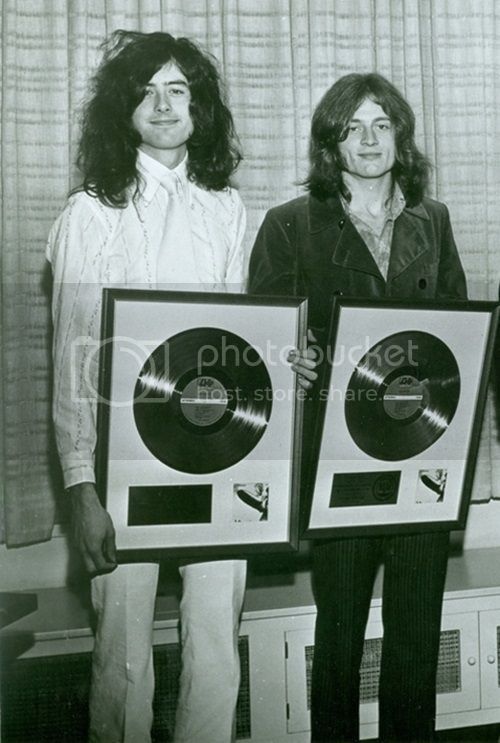 three people holding up two records in front of a window