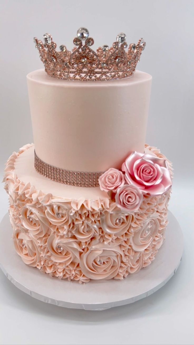 a three tiered cake decorated with pink roses and a crown on top, sitting on a white plate