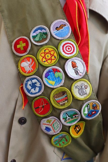 a man in a suit with many badges on his lapel and tie around his neck