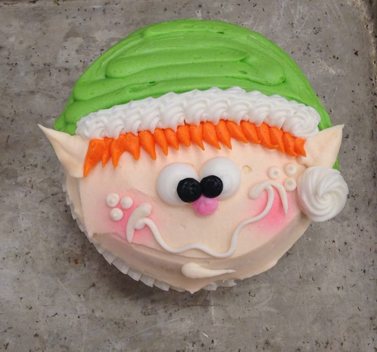 a decorated cupcake with green frosting and white icing on it's face