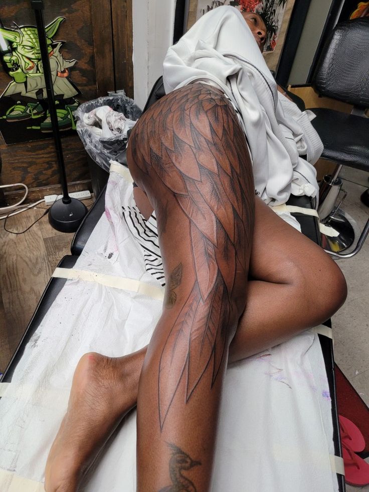 a man laying on top of a bed with tattoos on his arm and leg behind him