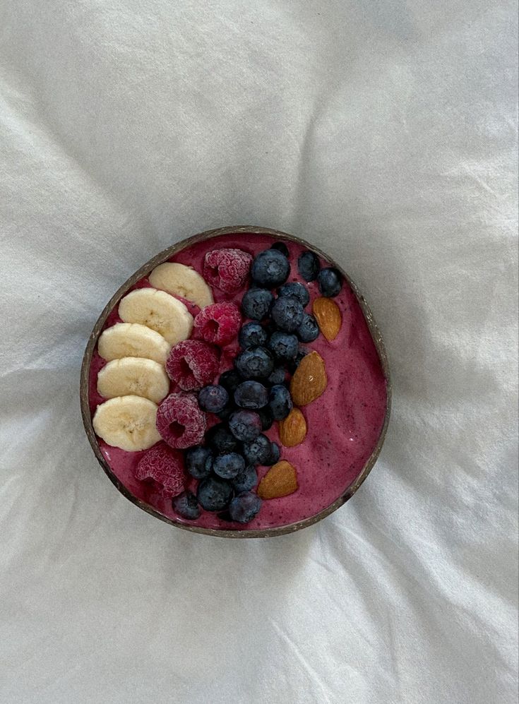 a bowl filled with fruit and nuts on top of a white sheet