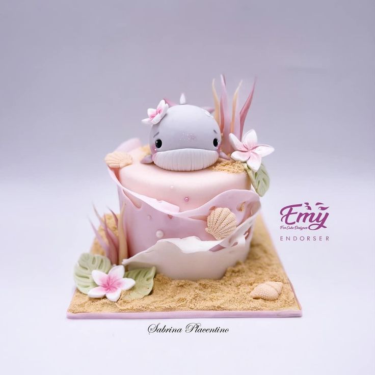 a pink cake decorated with an animal and seashells