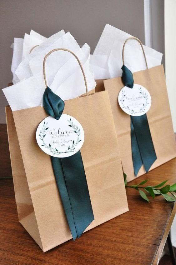 two brown paper bags with green ribbons on them sitting on top of a wooden table