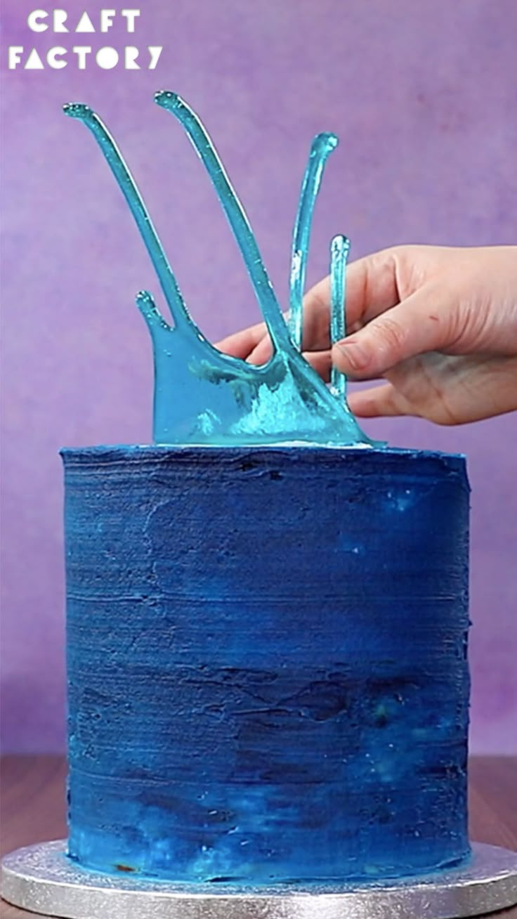 a person is decorating a blue cake with icing on the top and bottom