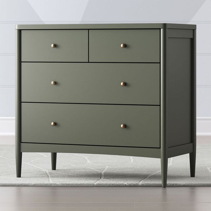 a green chest of drawers with gold knobs on the top and bottom, in front of a white wall