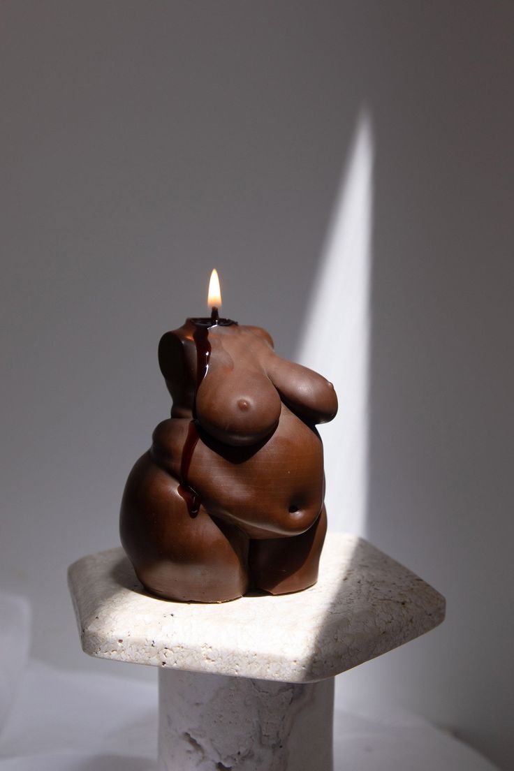 a candle that is sitting on top of a stone block in the shape of a bear