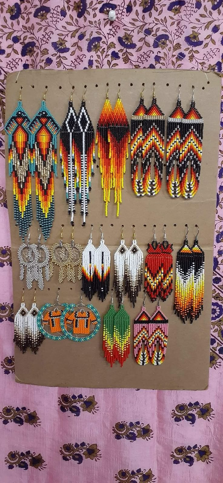 several pairs of beaded earrings hanging on a wall