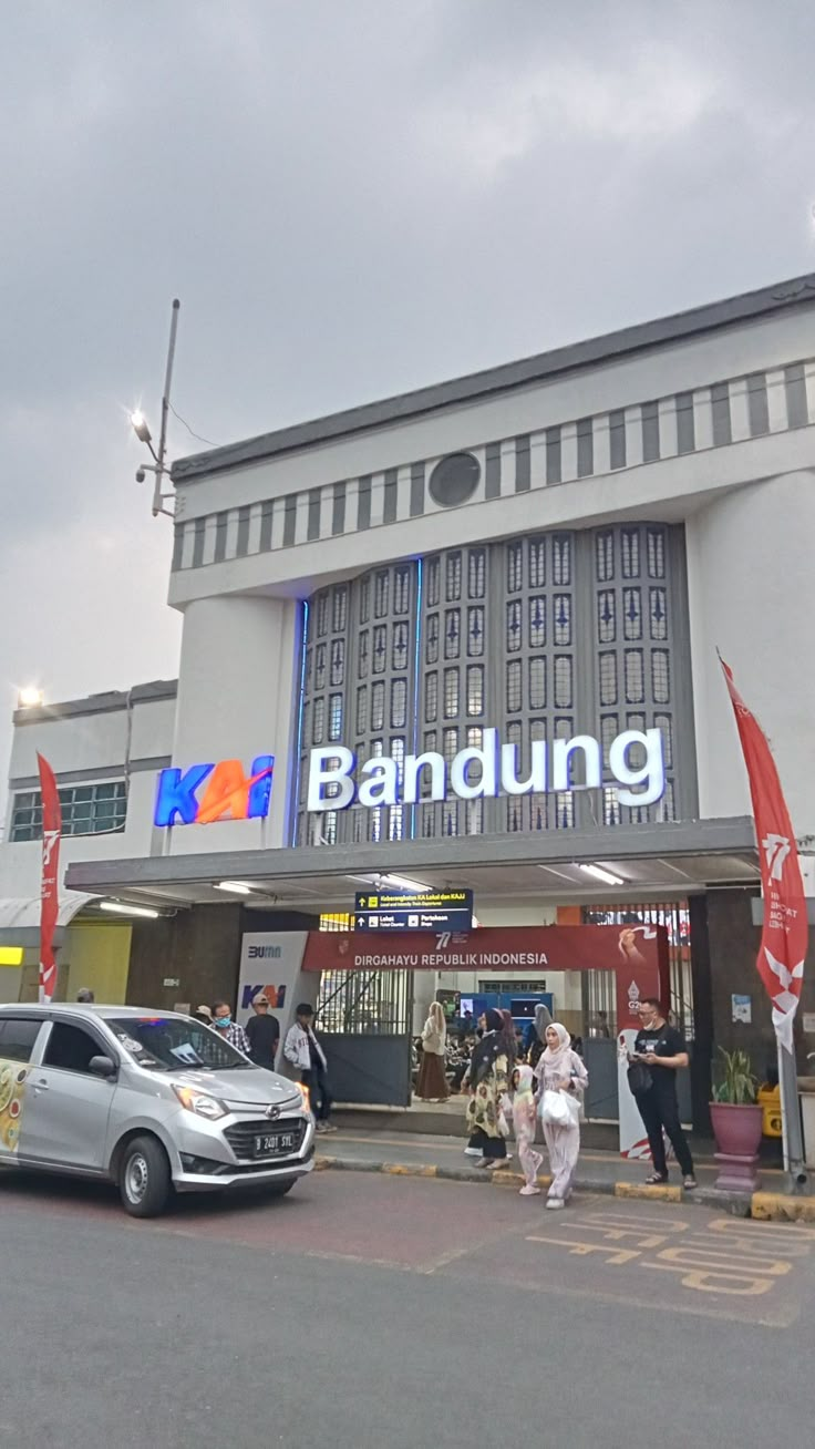 people are walking in front of a building that has a bandung sign on it