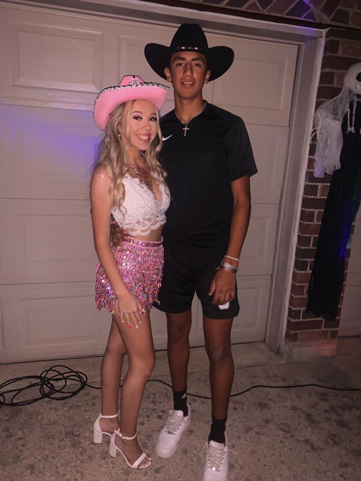 a man standing next to a woman wearing a pink cowboy hat and sequin skirt