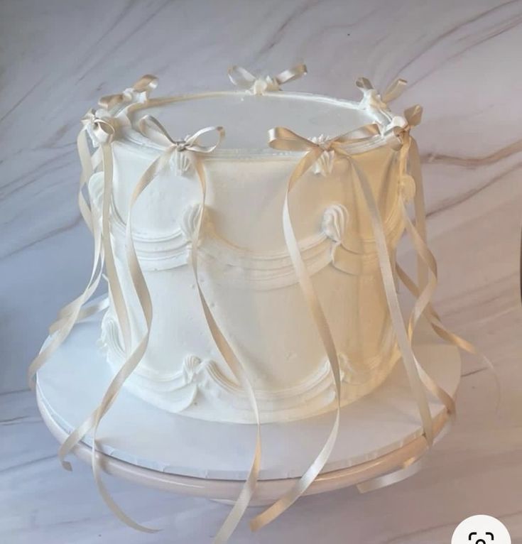 a white wedding cake with ribbons on top